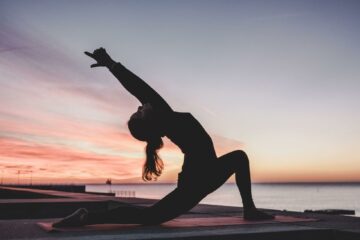 mujer haciendo postura de yoga al atardecer